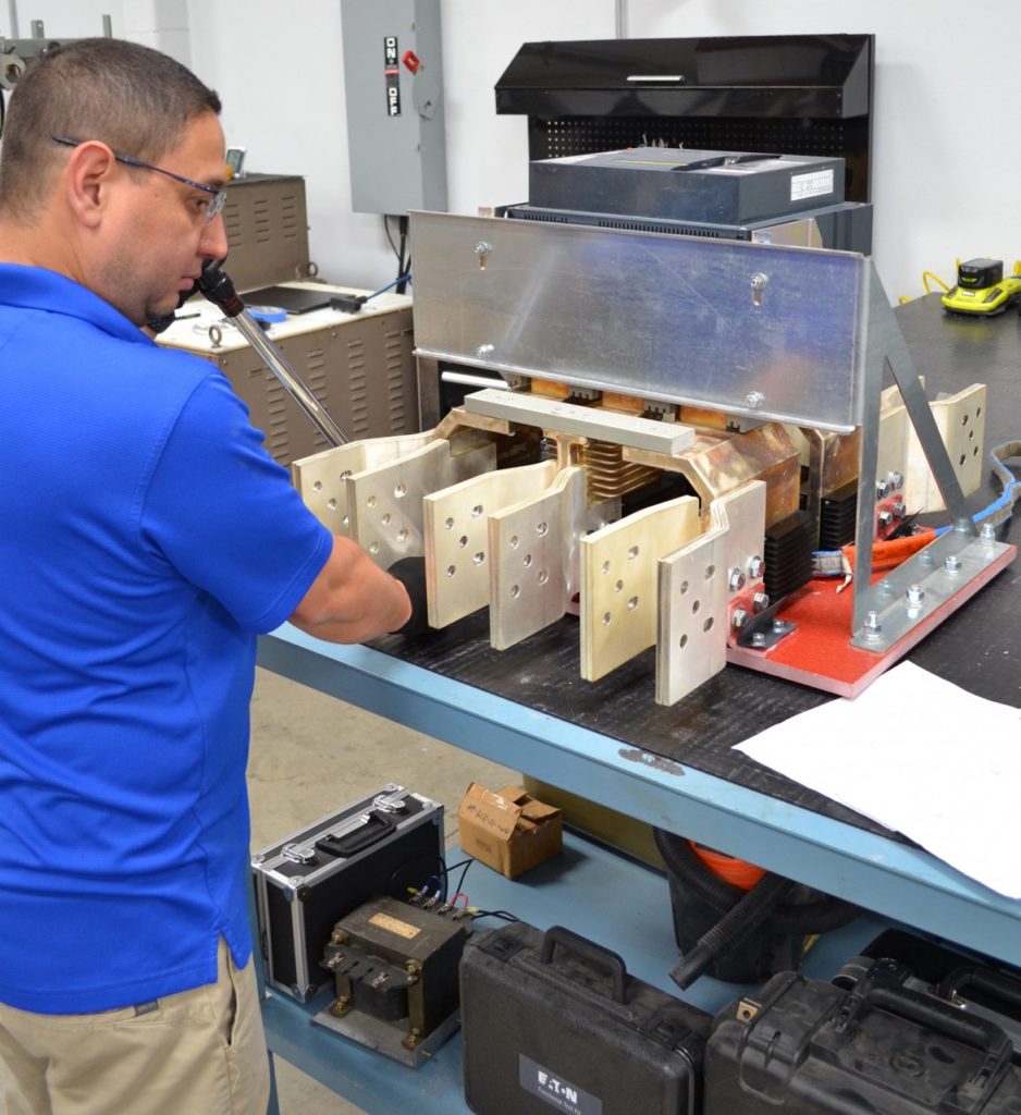 Technician working on large electrical equipment in workshop.