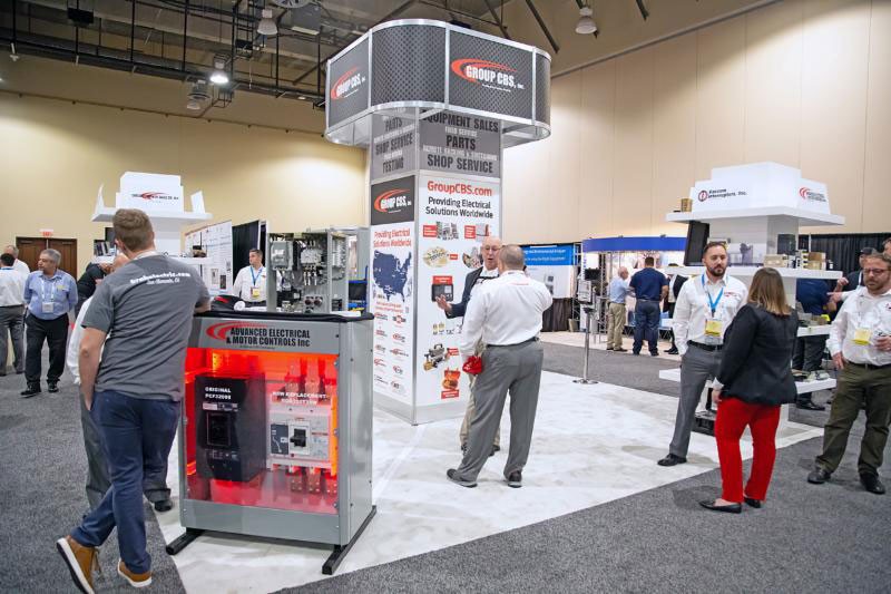 Electrical equipment trade show booth with attendees.